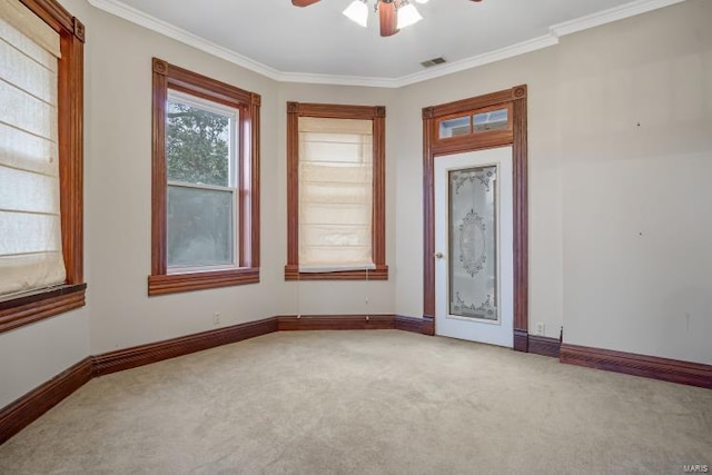 carpeted spare room featuring a ceiling fan, crown molding, and baseboards