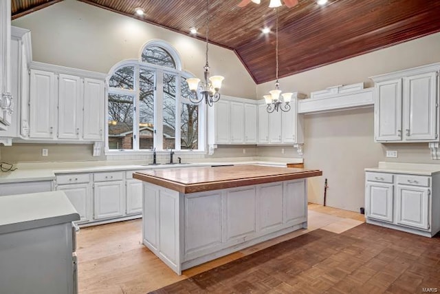 kitchen featuring wood ceiling, a chandelier, a sink, white cabinetry, and a kitchen island