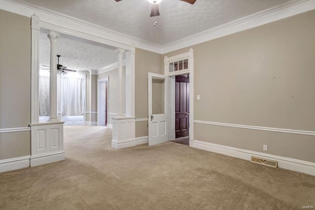 spare room featuring a ceiling fan, decorative columns, crown molding, carpet, and baseboards
