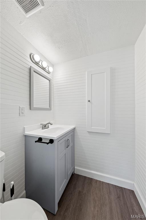 1919 Parker Rd, Saint Louis, MO 63138 - bathroom with baseboards, wood finished floors, vanity, a textured ceiling, and toilet
