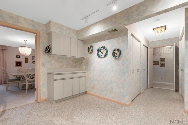 585 Coeur De Royale Dr Unit 206, Creve Coeur, MO 63141 - kitchen with light carpet, rail lighting, light countertops, wallpapered walls, and a chandelier