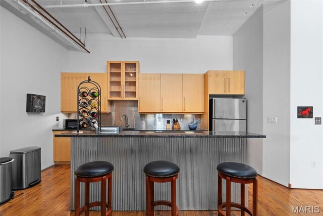 1010 Saint Charles St Unit 904, Saint Louis, MO 63101 - kitchen featuring freestanding refrigerator, decorative backsplash, a breakfast bar area, a kitchen island, and light wood finished floors