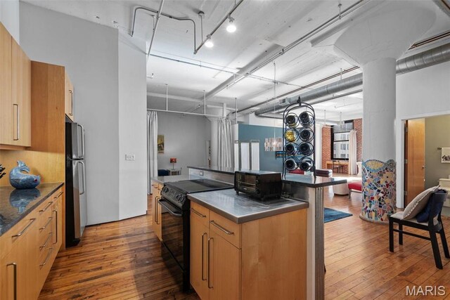 1010 Saint Charles St Unit 904, Saint Louis, MO 63101 - kitchen featuring black electric range, freestanding refrigerator, dark wood-style flooring, a kitchen island, and stainless steel countertops