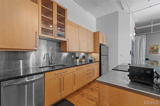 1010 Saint Charles St Unit 904, Saint Louis, MO 63101 - kitchen with appliances with stainless steel finishes, a sink, light wood finished floors, glass insert cabinets, and decorative backsplash