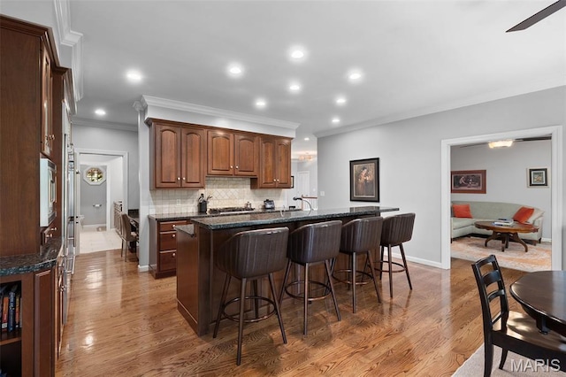 29 Spoede Ln, Creve Coeur, MO 63141 - kitchen with ornamental molding, a kitchen bar, a center island with sink, dark wood finished floors, and backsplash