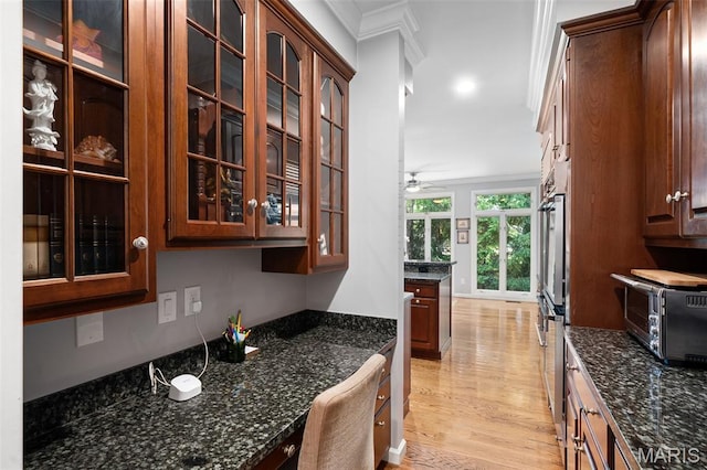 29 Spoede Ln, Creve Coeur, MO 63141 - kitchen featuring ornamental molding, light wood finished floors, glass insert cabinets, dark stone counters, and a ceiling fan