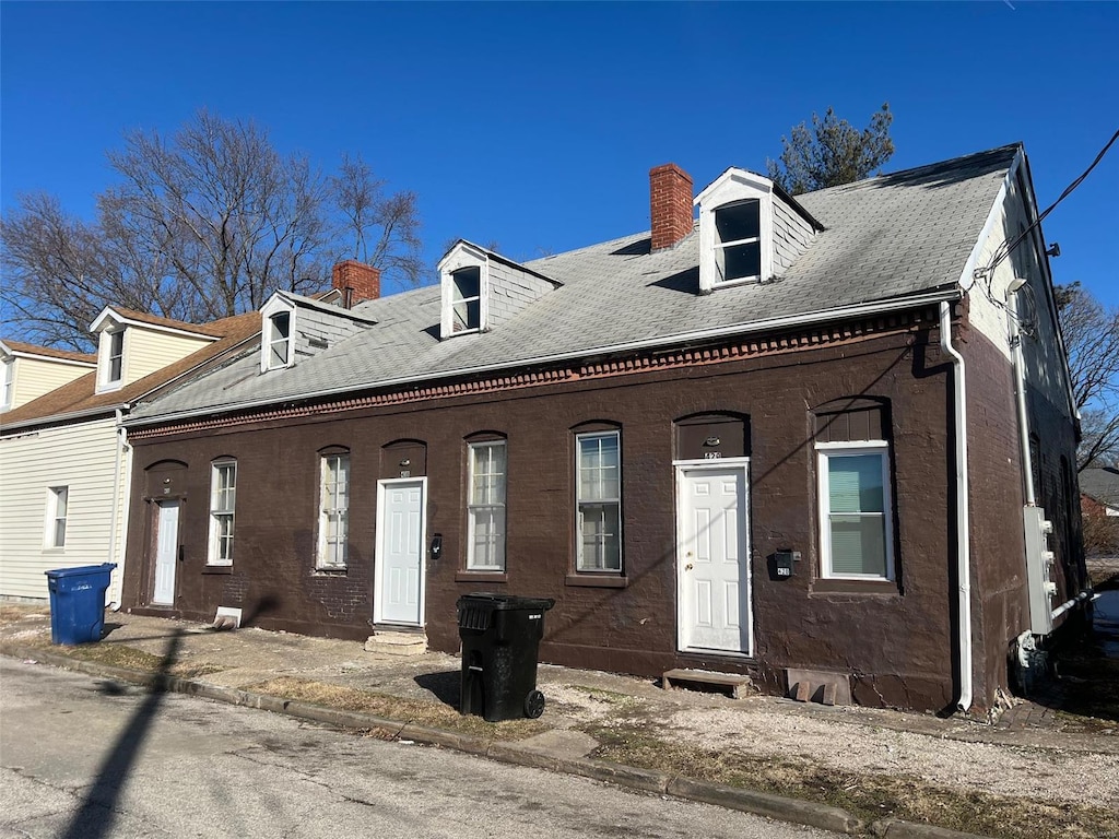 view of front of home with a chimney, brick siding, and entry steps