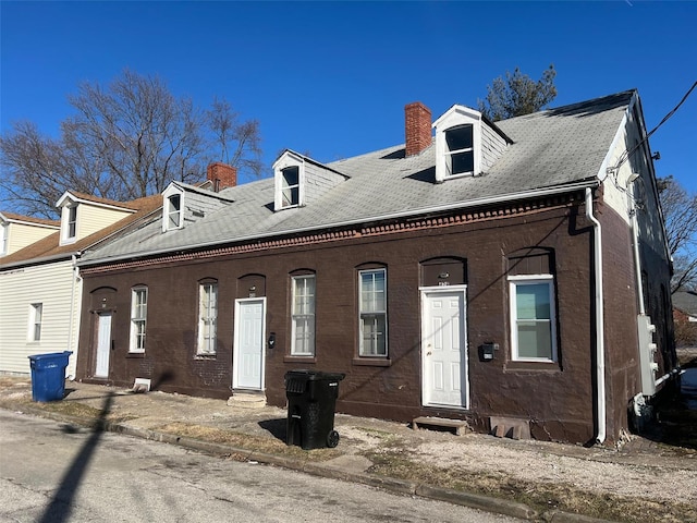 view of front of home with a chimney, brick siding, and entry steps