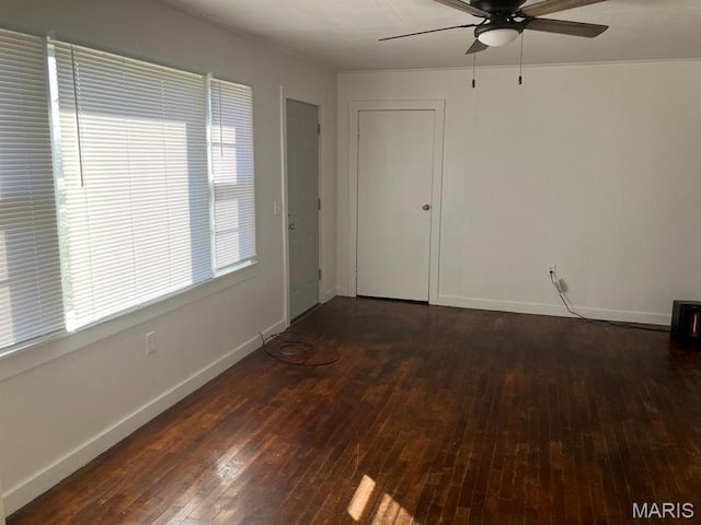 spare room with ceiling fan, dark wood-type flooring, and baseboards