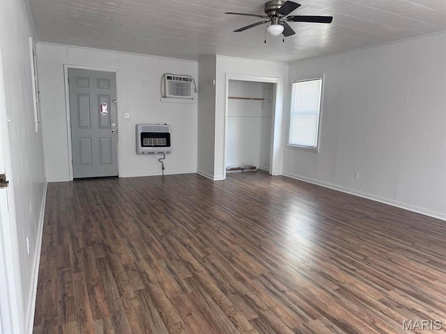 unfurnished bedroom featuring heating unit, dark wood-type flooring, an AC wall unit, a closet, and baseboards