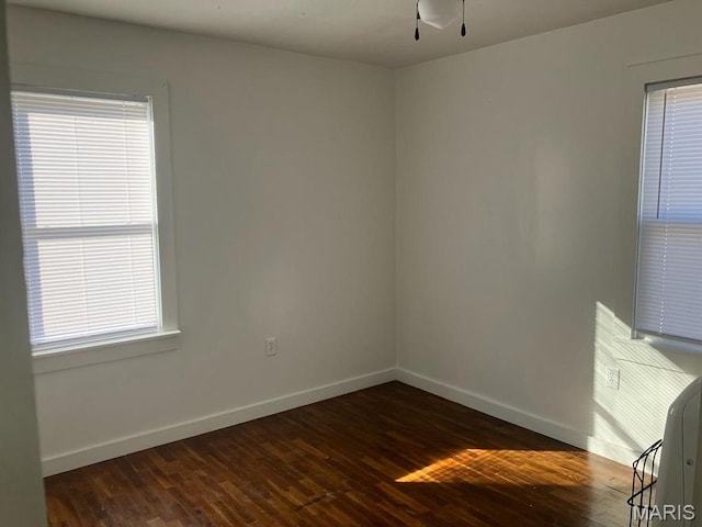 unfurnished room with baseboards, dark wood-type flooring, and a ceiling fan