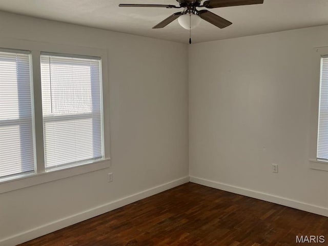 empty room featuring baseboards, ceiling fan, and dark wood-style flooring
