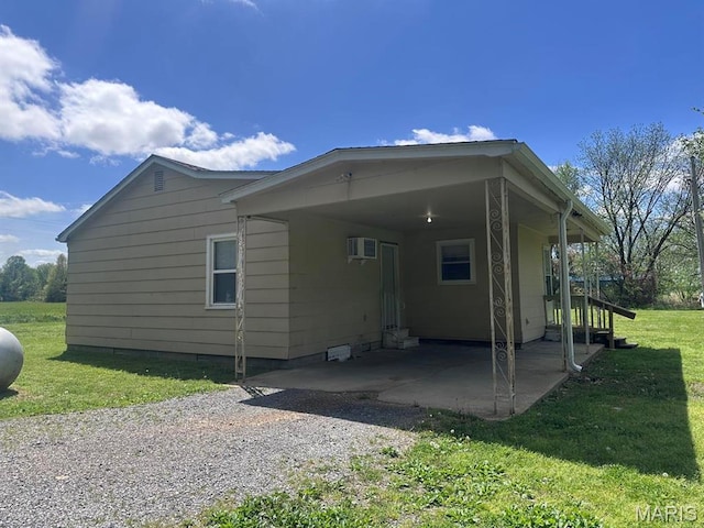 view of side of home featuring crawl space, a lawn, a carport, and a wall unit AC