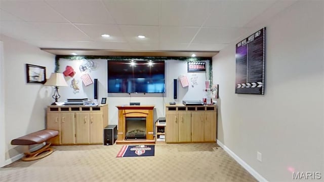 carpeted living room featuring a drop ceiling, baseboards, recessed lighting, and a fireplace