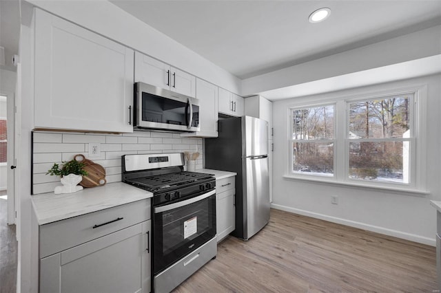 17 S Floridale Dr, Saint Louis, MO 63135 - kitchen featuring stainless steel appliances, baseboards, tasteful backsplash, light countertops, and light wood-style floors