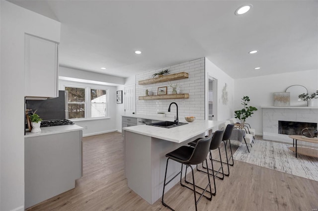 17 S Floridale Dr, Saint Louis, MO 63135 - kitchen with a sink, backsplash, a kitchen bar, light wood finished floors, and a high end fireplace