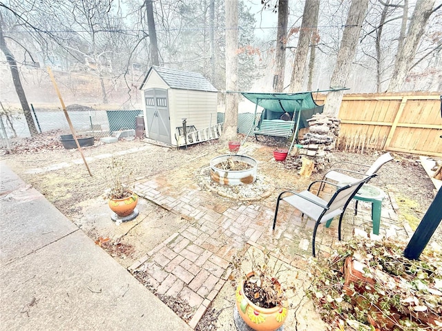 10063 Mockingbird Dr, Holiday Shores, MO 63624 - view of patio / terrace with a storage shed, a fenced backyard, an outdoor structure, and an outdoor fire pit