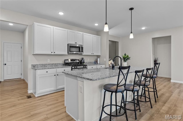 138 Rhythm Point Dr, Saint Peters, MO 63376 - kitchen with stainless steel appliances, light wood-type flooring, a sink, white cabinetry, and recessed lighting