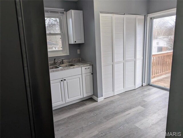 10544 Decker Ave, Saint Louis, MO 63114 - kitchen with a sink, light wood finished floors, white cabinets, and baseboards