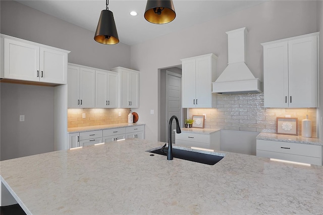 1035 Morgan Meadow Dr, Wentzville, MO 63385 - kitchen with premium range hood, a sink, decorative backsplash, light stone counters, and hanging light fixtures