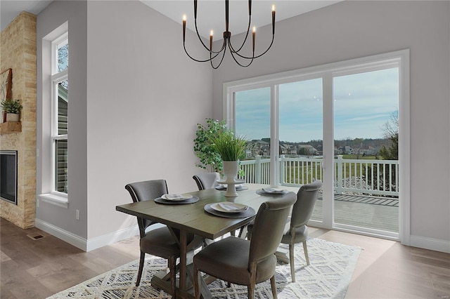 1035 Morgan Meadow Dr, Wentzville, MO 63385 - dining room featuring baseboards, light wood-style flooring, a chandelier, and a large fireplace