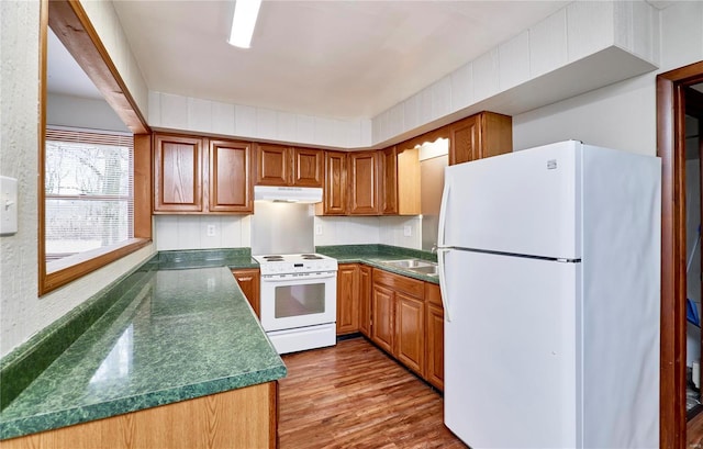 1991 State Highway H, Sikeston, MO 63780 - kitchen featuring white appliances, under cabinet range hood, dark countertops, wood finished floors, and brown cabinetry