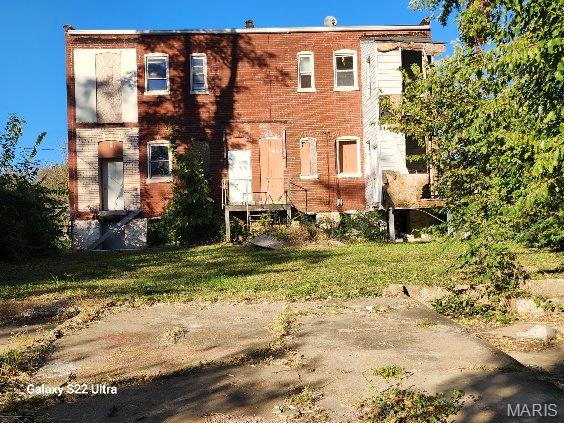 back of house featuring a yard and brick siding