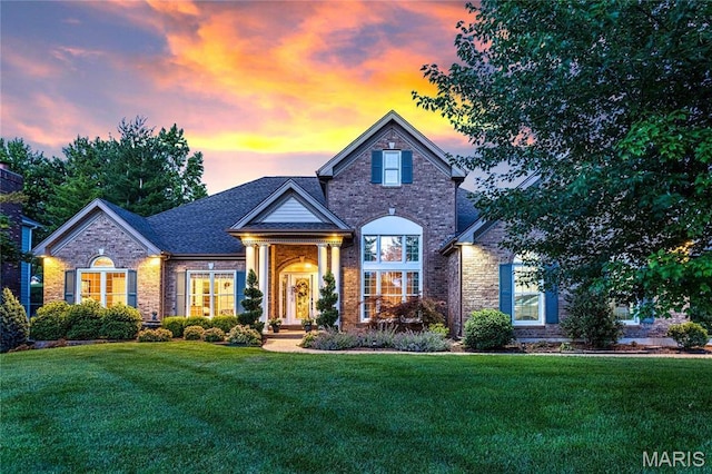 view of front of home featuring a front yard, brick siding, and stone siding