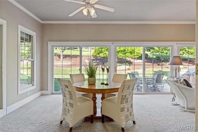 carpeted dining space with ceiling fan, crown molding, and baseboards