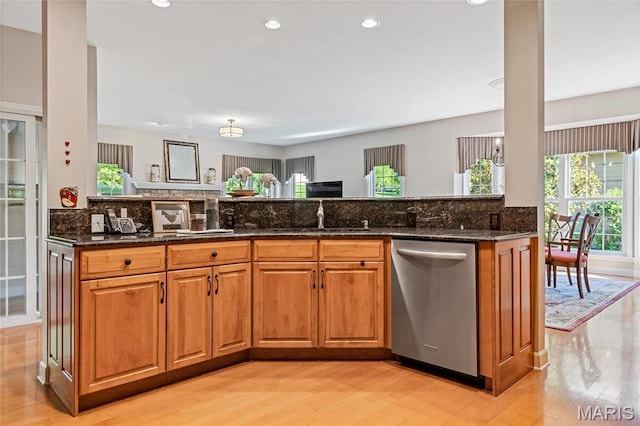 kitchen with stainless steel dishwasher, a sink, brown cabinets, tasteful backsplash, and recessed lighting