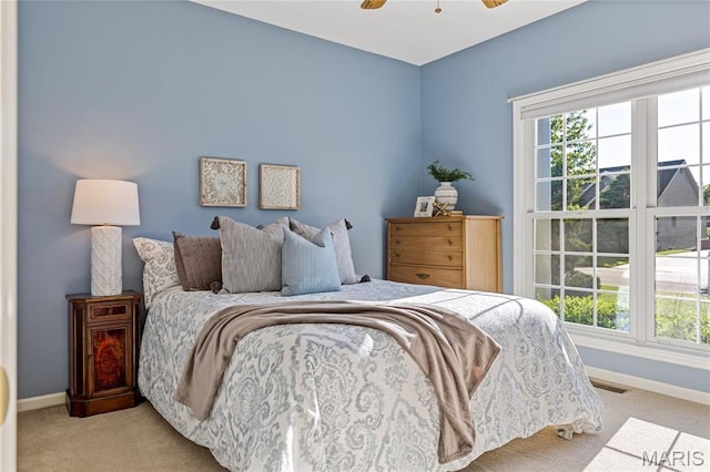 carpeted bedroom featuring baseboards, multiple windows, and ceiling fan