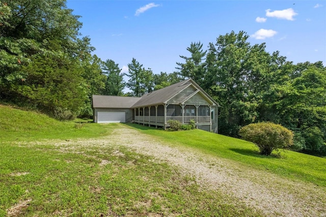 view of front of house with a sunroom, dirt driveway, an attached garage, and a front yard