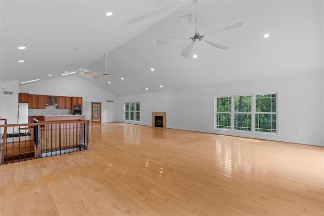 unfurnished living room featuring high vaulted ceiling, ceiling fan, light wood-type flooring, a sink, and recessed lighting