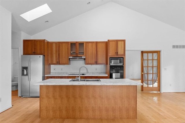 kitchen featuring black appliances, high vaulted ceiling, a sink, a skylight, and light countertops