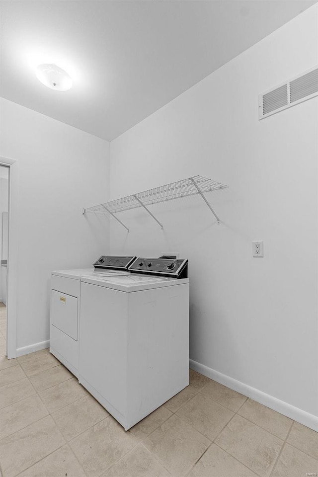 laundry room featuring independent washer and dryer, baseboards, and light tile patterned floors