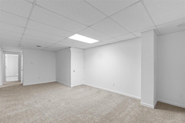 finished below grade area with a paneled ceiling, carpet, and baseboards