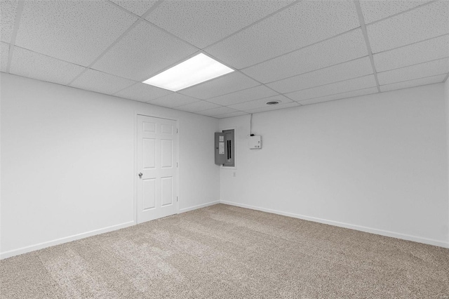 carpeted empty room with a paneled ceiling, electric panel, and baseboards