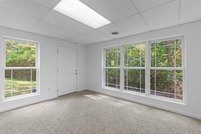 empty room featuring a paneled ceiling, plenty of natural light, carpet floors, and baseboards