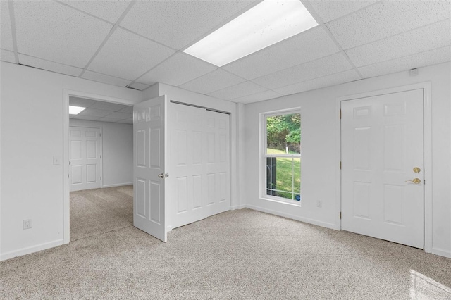 basement with a paneled ceiling, carpet flooring, and baseboards