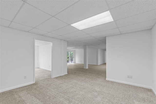 basement with carpet floors, a drop ceiling, and baseboards