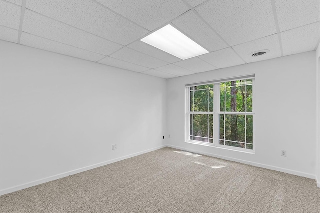 spare room featuring a drop ceiling, baseboards, and carpet flooring
