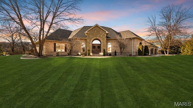 view of front of home featuring a yard, brick siding, and stone siding
