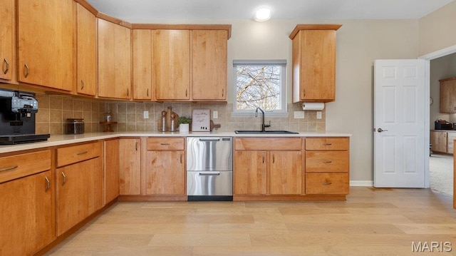 kitchen with dishwasher, a sink, light wood-type flooring, light countertops, and backsplash