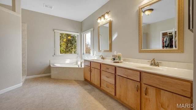 bathroom featuring a bath, double vanity, and baseboards