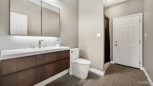 full bathroom featuring a stall shower, toilet, vanity, and baseboards