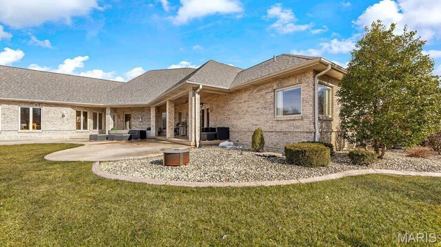 back of property featuring brick siding, a lawn, a patio, and roof with shingles