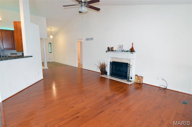 936 Palamino Path, High Ridge, MO 63049 - unfurnished living room featuring a tile fireplace, a ceiling fan, wood finished floors, high vaulted ceiling, and ornate columns