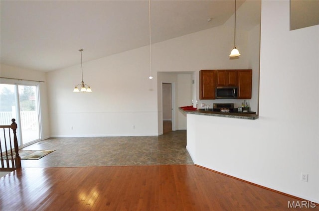 936 Palamino Path, High Ridge, MO 63049 - kitchen with stainless steel microwave, range, dark countertops, hanging light fixtures, and high vaulted ceiling