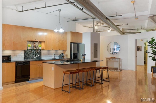 1619 Washington Ave Unit 805, Saint Louis, MO 63103 - kitchen featuring black appliances, a breakfast bar area, a kitchen island, dark countertops, and light wood-type flooring