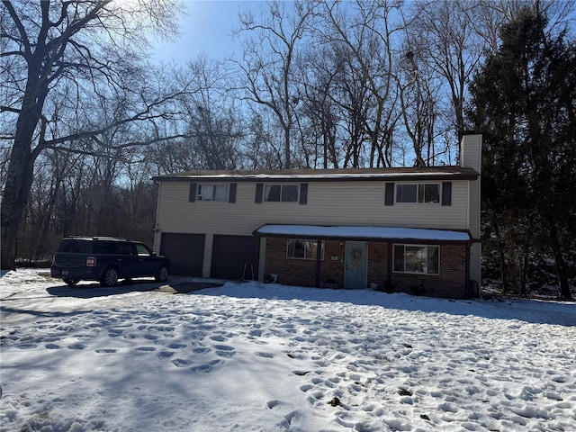 view of front of house featuring a chimney, an attached garage, and brick siding